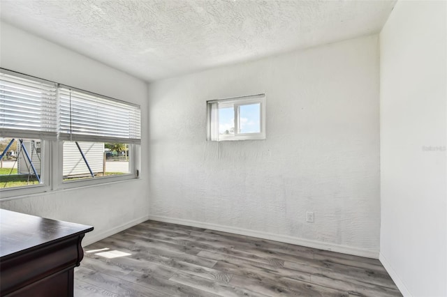 empty room featuring a textured ceiling, hardwood / wood-style flooring, and a wealth of natural light