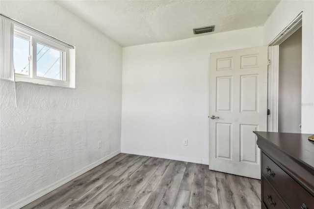 unfurnished bedroom with light hardwood / wood-style floors and a textured ceiling