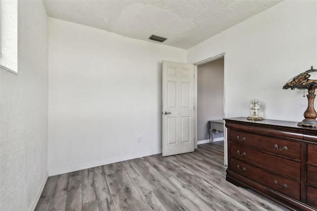 bedroom with light hardwood / wood-style floors and a textured ceiling