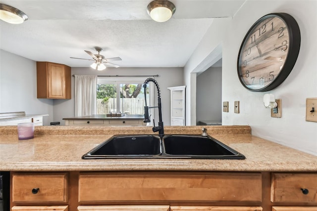 kitchen with a textured ceiling, sink, and ceiling fan