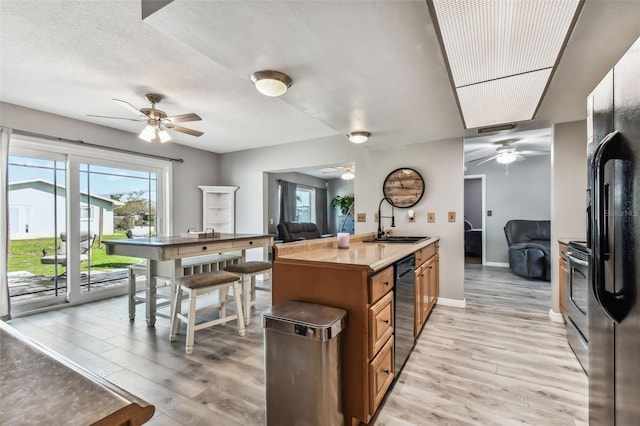 kitchen with light hardwood / wood-style floors, stainless steel appliances, a textured ceiling, and sink