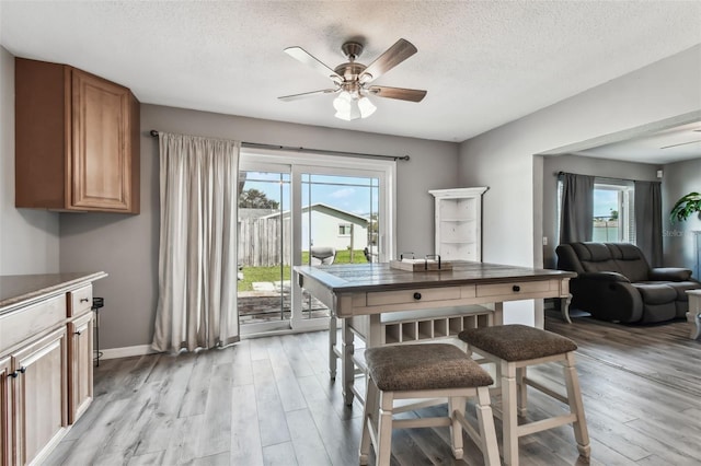 dining area with light hardwood / wood-style flooring, a textured ceiling, and ceiling fan