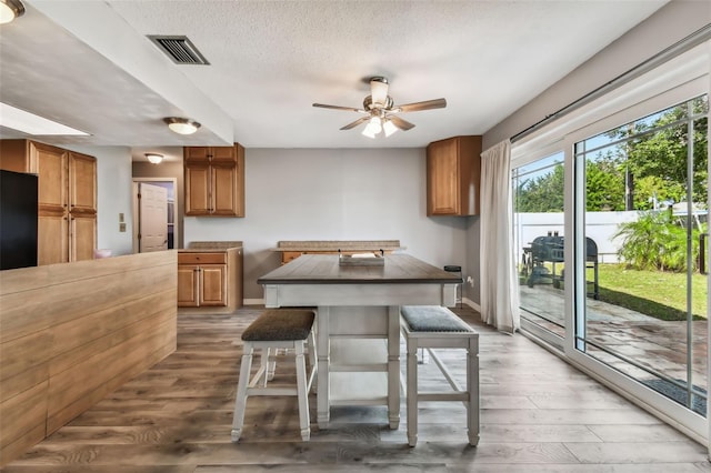 dining room with dark wood-type flooring, ceiling fan, and a textured ceiling