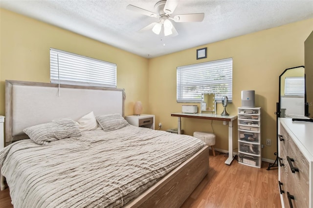 bedroom with a textured ceiling, light wood-type flooring, and ceiling fan