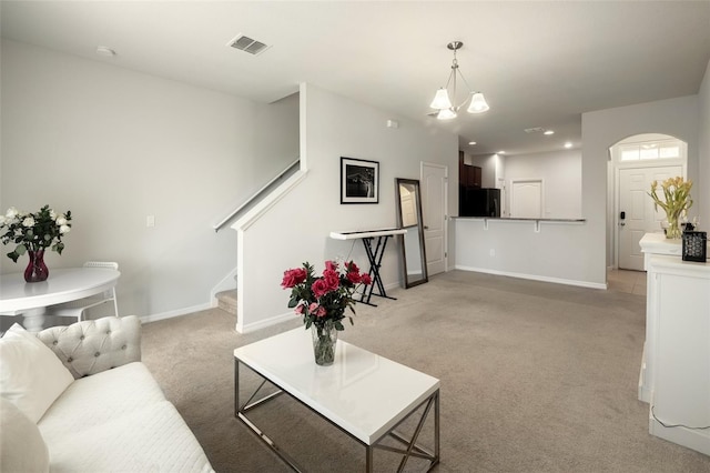 carpeted living room with an inviting chandelier