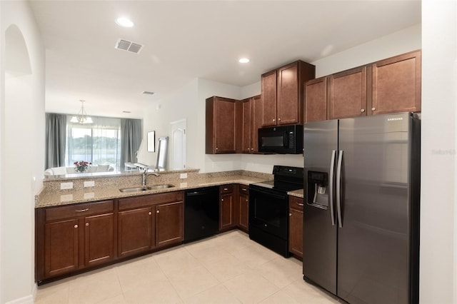 kitchen featuring light stone counters, black appliances, sink, kitchen peninsula, and hanging light fixtures