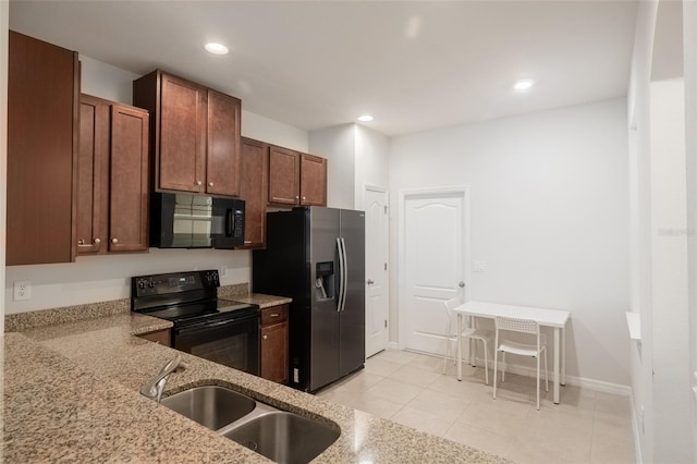 kitchen with light stone counters, light tile patterned flooring, sink, and black appliances