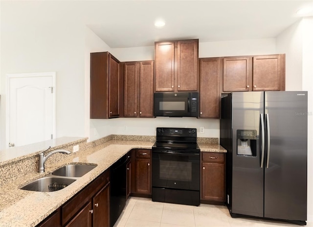 kitchen featuring light tile patterned flooring, black appliances, light stone counters, and sink