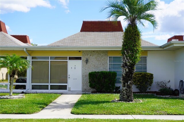 4338 Tahitian Gardens Cir Unit C, Holiday, FL 34691 - view of front of home featuring stucco siding, a shingled roof, and a front yard