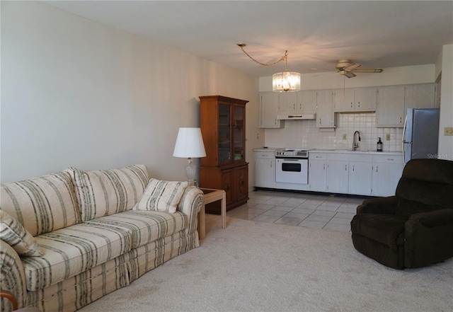 carpeted living room featuring ceiling fan with notable chandelier and sink