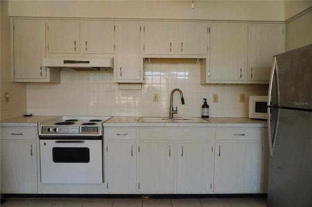 kitchen featuring white electric range oven, sink, tasteful backsplash, stainless steel refrigerator, and tile patterned floors