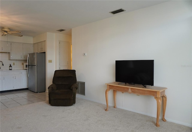 living room featuring light carpet, ceiling fan, and sink