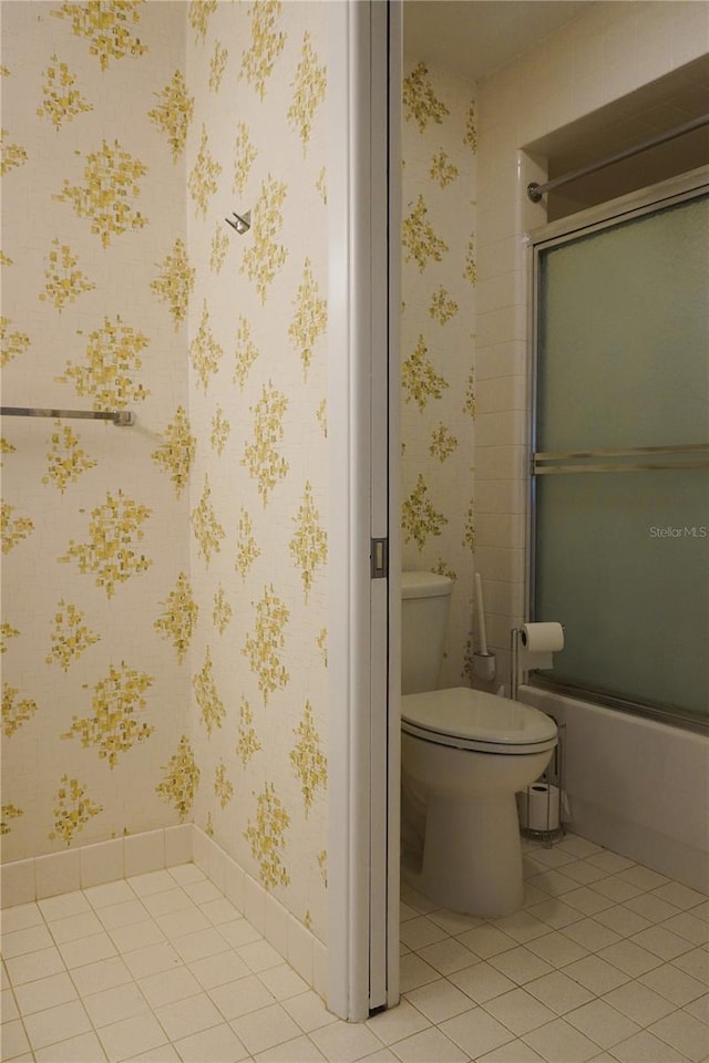 bathroom with bath / shower combo with glass door, tile patterned flooring, and toilet