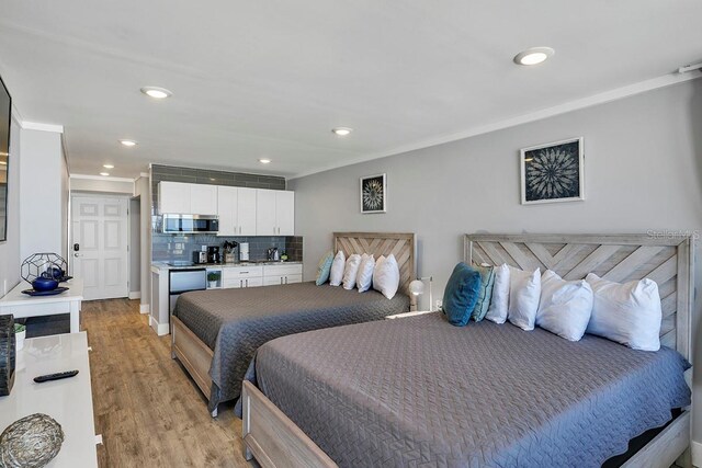 bedroom with crown molding, sink, and light wood-type flooring