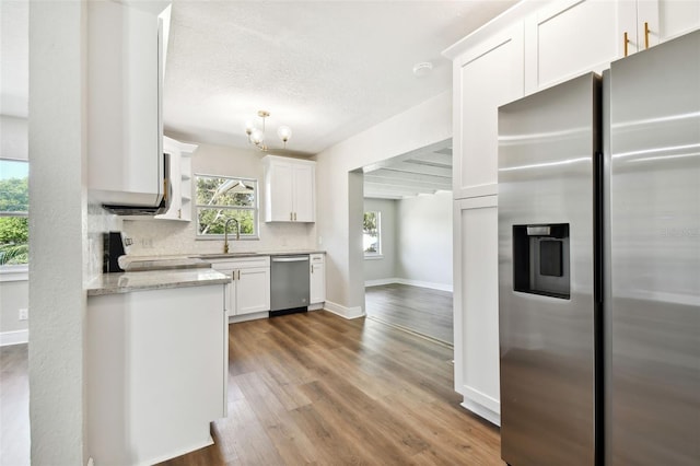 kitchen featuring sink, stainless steel appliances, light stone counters, wood-type flooring, and white cabinets