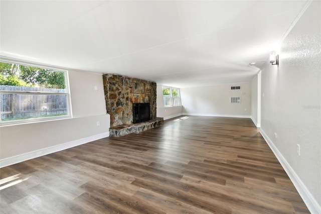 unfurnished living room featuring a stone fireplace and dark hardwood / wood-style flooring