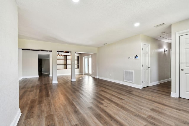 unfurnished living room with a textured ceiling and dark wood-type flooring