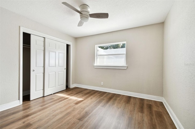 unfurnished bedroom featuring hardwood / wood-style floors, ceiling fan, and a closet