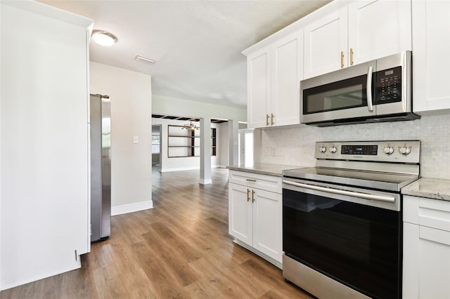 kitchen featuring light stone countertops, appliances with stainless steel finishes, light hardwood / wood-style floors, and white cabinetry