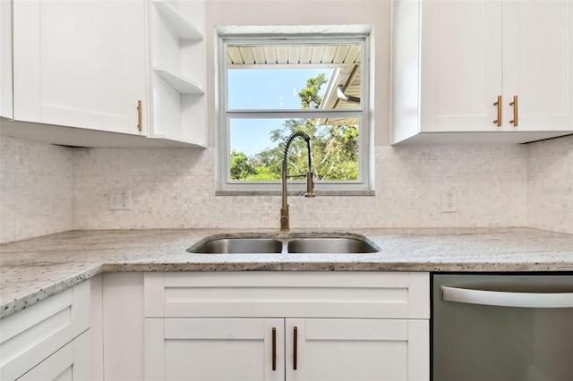 kitchen with stainless steel dishwasher, light stone counters, white cabinets, and sink