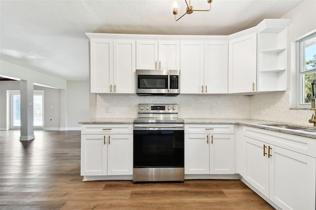 kitchen with white cabinets, dark hardwood / wood-style flooring, light stone countertops, and appliances with stainless steel finishes