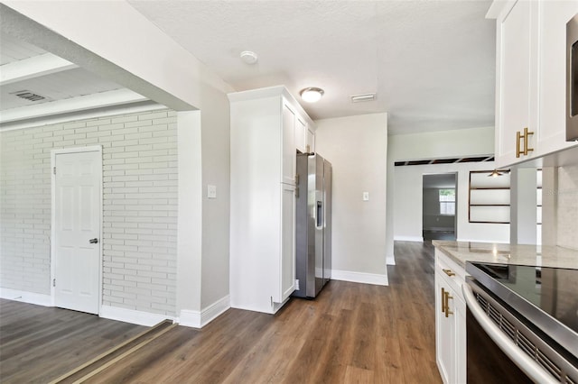 kitchen with light stone countertops, appliances with stainless steel finishes, dark hardwood / wood-style floors, and white cabinetry