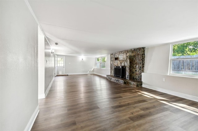 unfurnished living room featuring dark hardwood / wood-style floors and a stone fireplace