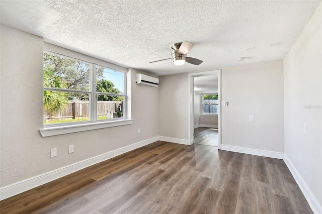 spare room featuring a wall mounted AC, ceiling fan, dark hardwood / wood-style flooring, and a textured ceiling