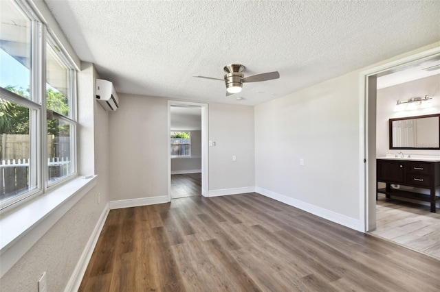 spare room with a textured ceiling, ceiling fan, hardwood / wood-style floors, and a wall mounted air conditioner