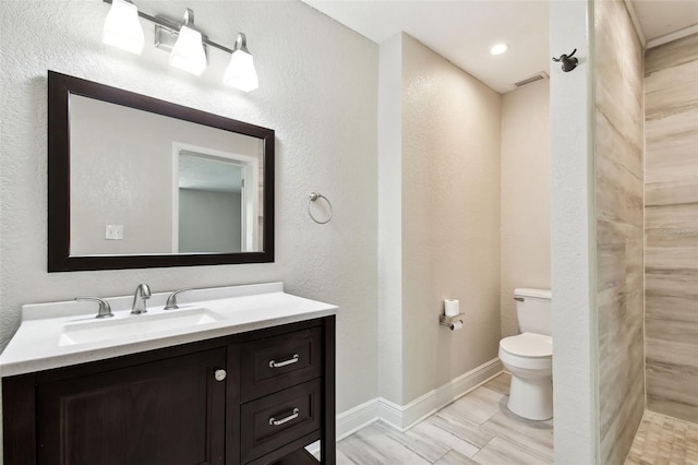 bathroom featuring a shower, vanity, and toilet