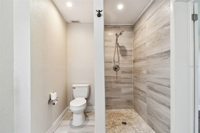 bathroom featuring tiled shower, hardwood / wood-style floors, and toilet