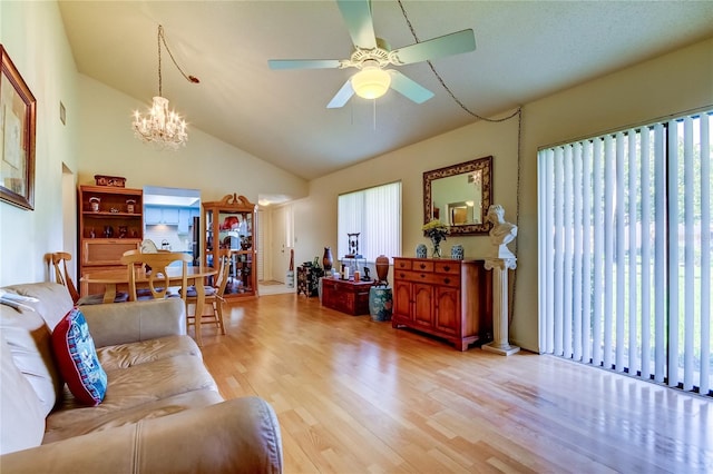 living room featuring ceiling fan with notable chandelier, light wood-type flooring, and high vaulted ceiling