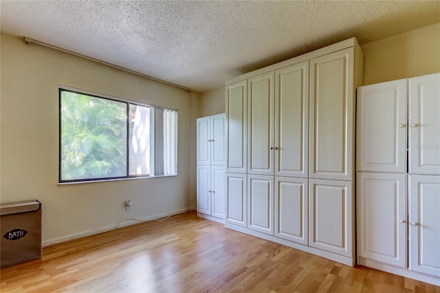 unfurnished bedroom featuring a closet, light hardwood / wood-style floors, and a textured ceiling