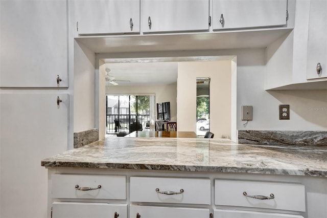 kitchen with white cabinets, light stone counters, and ceiling fan