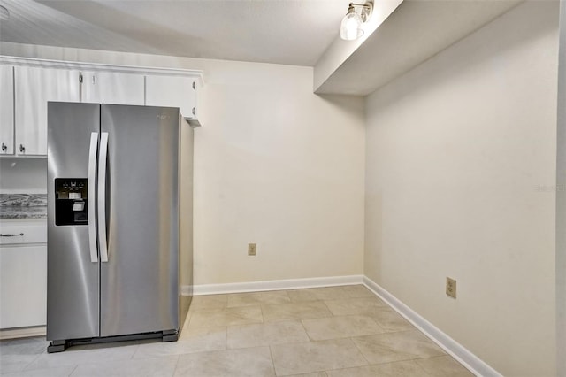 kitchen featuring stainless steel fridge, white cabinets, and light tile patterned floors