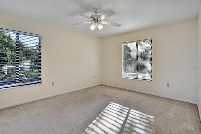 carpeted empty room featuring a wealth of natural light and ceiling fan