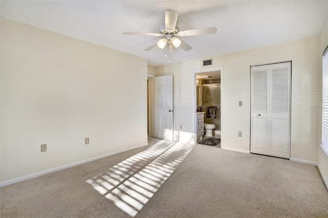 unfurnished bedroom featuring ensuite bathroom, ceiling fan, light carpet, and a closet