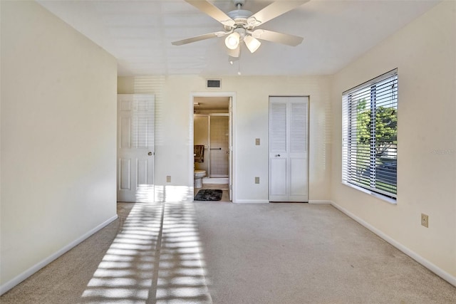 unfurnished bedroom featuring light carpet, connected bathroom, a closet, and ceiling fan