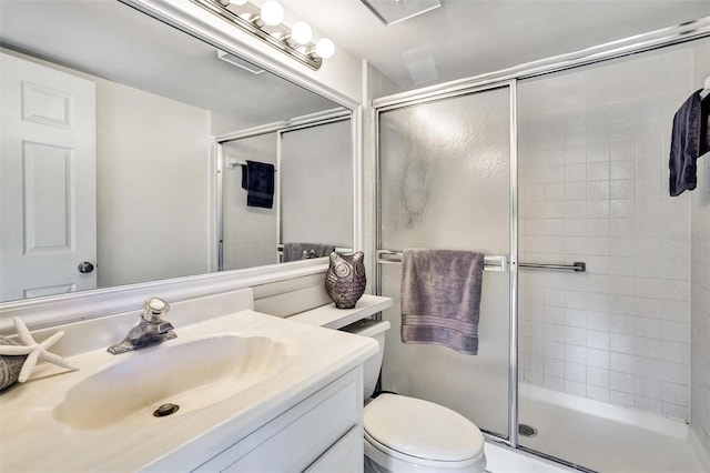 bathroom with a shower with door, vanity, and toilet