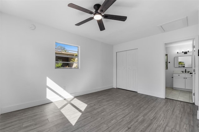 unfurnished bedroom with sink, ensuite bath, light hardwood / wood-style floors, and a closet