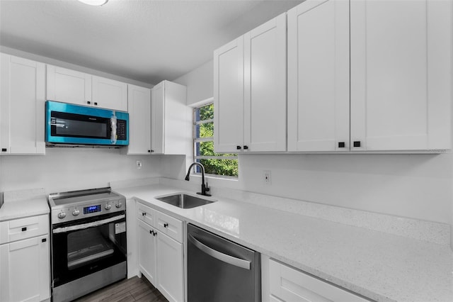 kitchen with light stone counters, sink, stainless steel appliances, and white cabinets