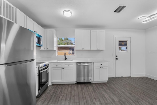 kitchen with sink, dark hardwood / wood-style floors, white cabinets, and appliances with stainless steel finishes