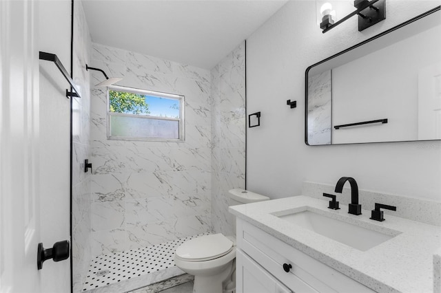 bathroom with vanity, a tile shower, and toilet