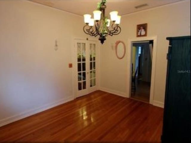 unfurnished dining area with french doors, dark hardwood / wood-style floors, and an inviting chandelier