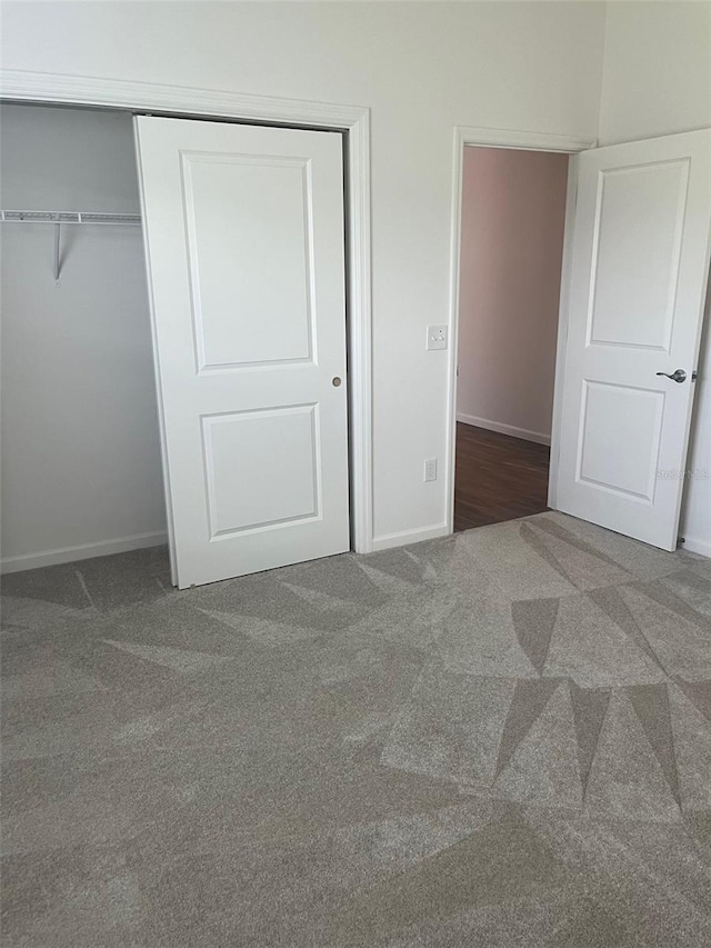 unfurnished bedroom with dark carpet and a closet