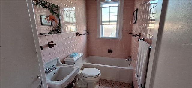 bathroom with sink, a healthy amount of sunlight, toilet, and tile walls