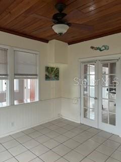 tiled spare room with french doors, ceiling fan, a wealth of natural light, and wood ceiling