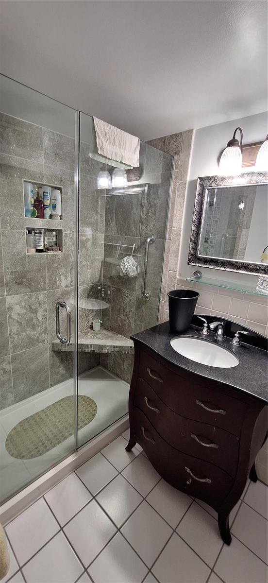 bathroom with tile patterned flooring, vanity, and a shower with shower door