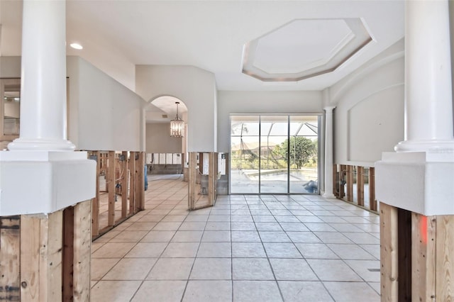 interior space with light tile patterned flooring, ornate columns, and a raised ceiling