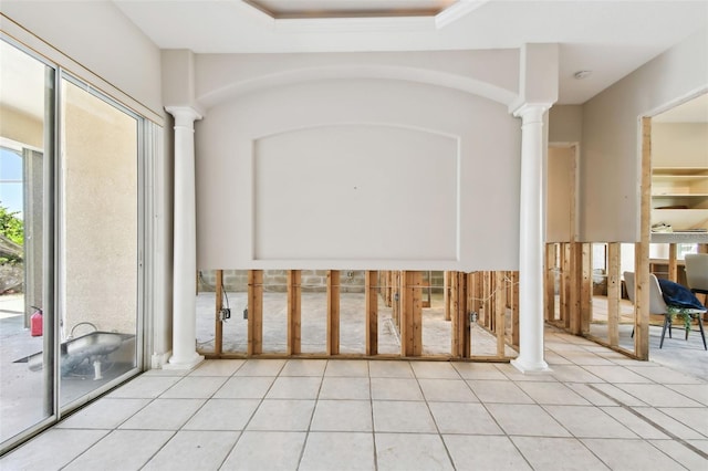 interior space with light tile patterned flooring, decorative columns, and a raised ceiling